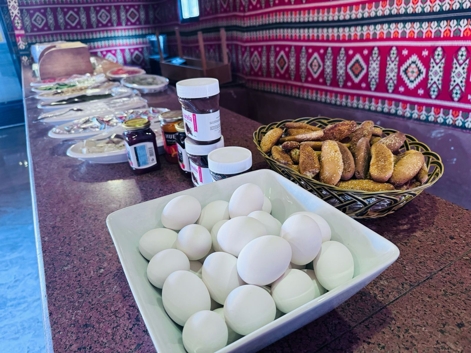 Una mesa de buffet con diferentes opciones de comida, incluyendo un bol de panecillos y una bandeja de huevos.