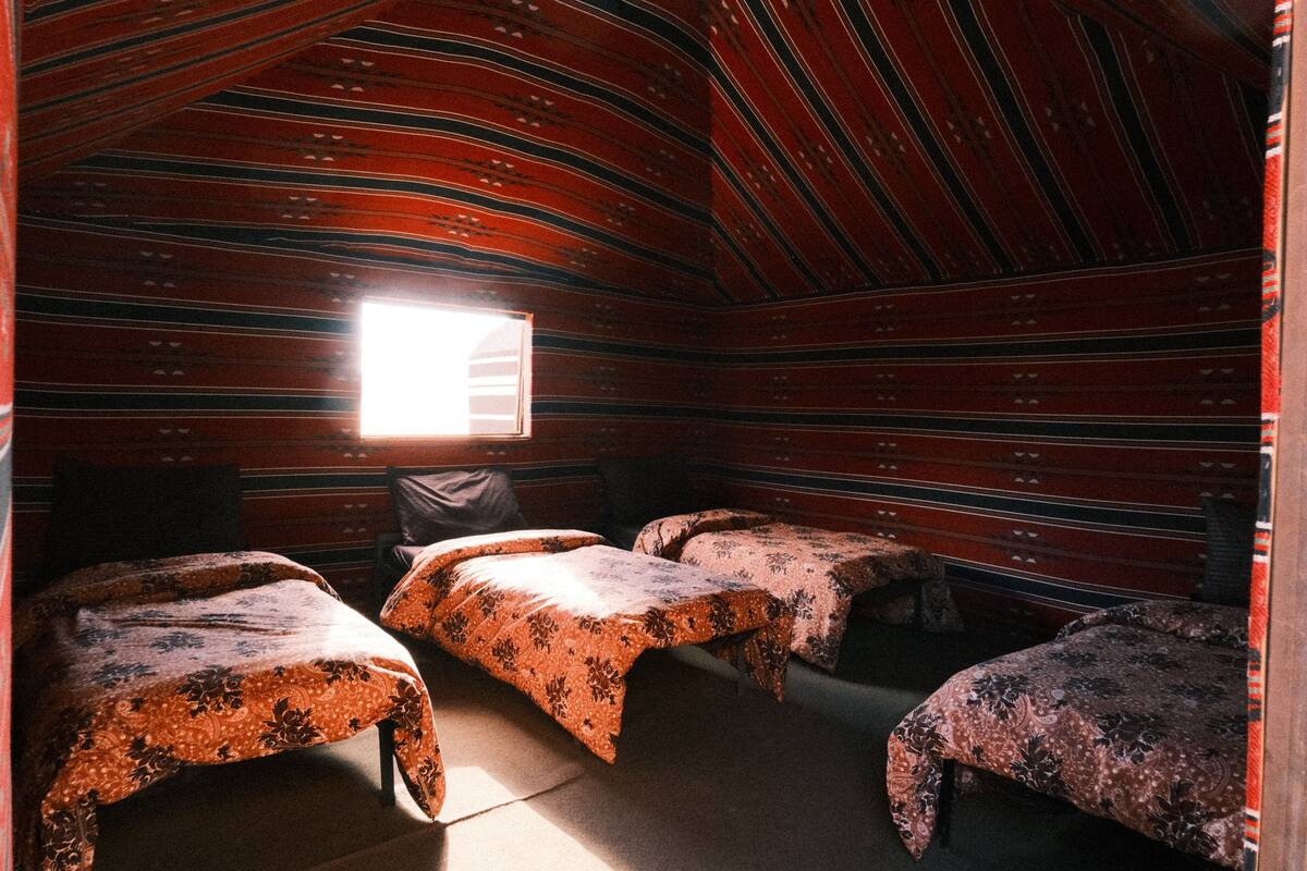 Una habitación con tres camas, una ventana y techo inclinado.