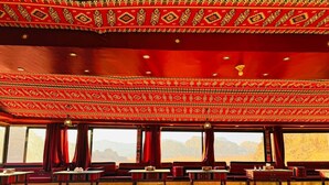 A room with a patterned red ceiling, multiple windows, and seating areas. - Wadi Rum Magic Nature Camp (Wadi Rum)