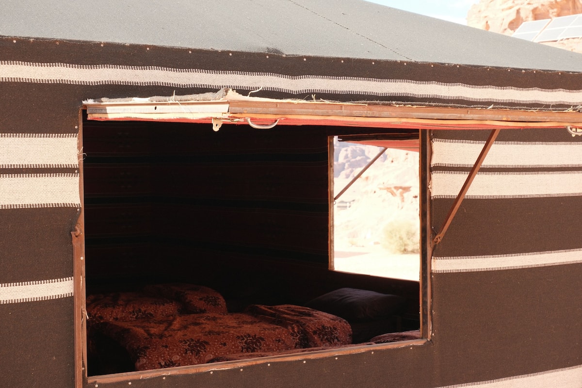 Tienda con ventana, cama en su interior y vista al exterior.