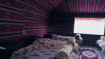 Une chambre avec une couvre-lit à motifs, une fenêtre donnant sur un beau paysage et un tapis à motifs.