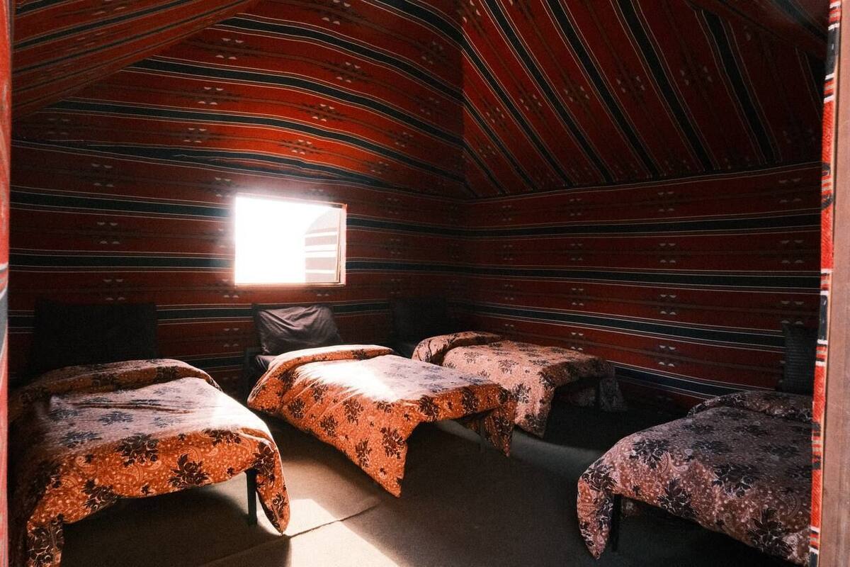 Habitación con tres camas, una ventana y techo a rayas.