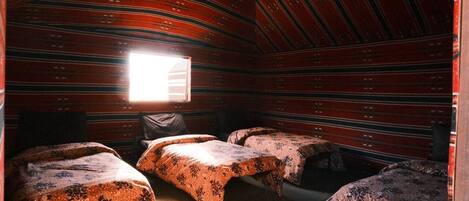 A room with three beds, a window, and a striped ceiling.