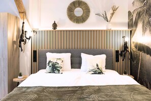 A modern bedroom with a bed, two pillows, a wall-mounted mirror, and a decorative plant. - BaliApartment, kitchen, parking lot, 24h digital check-in, Wlan 150MBit (Hof)