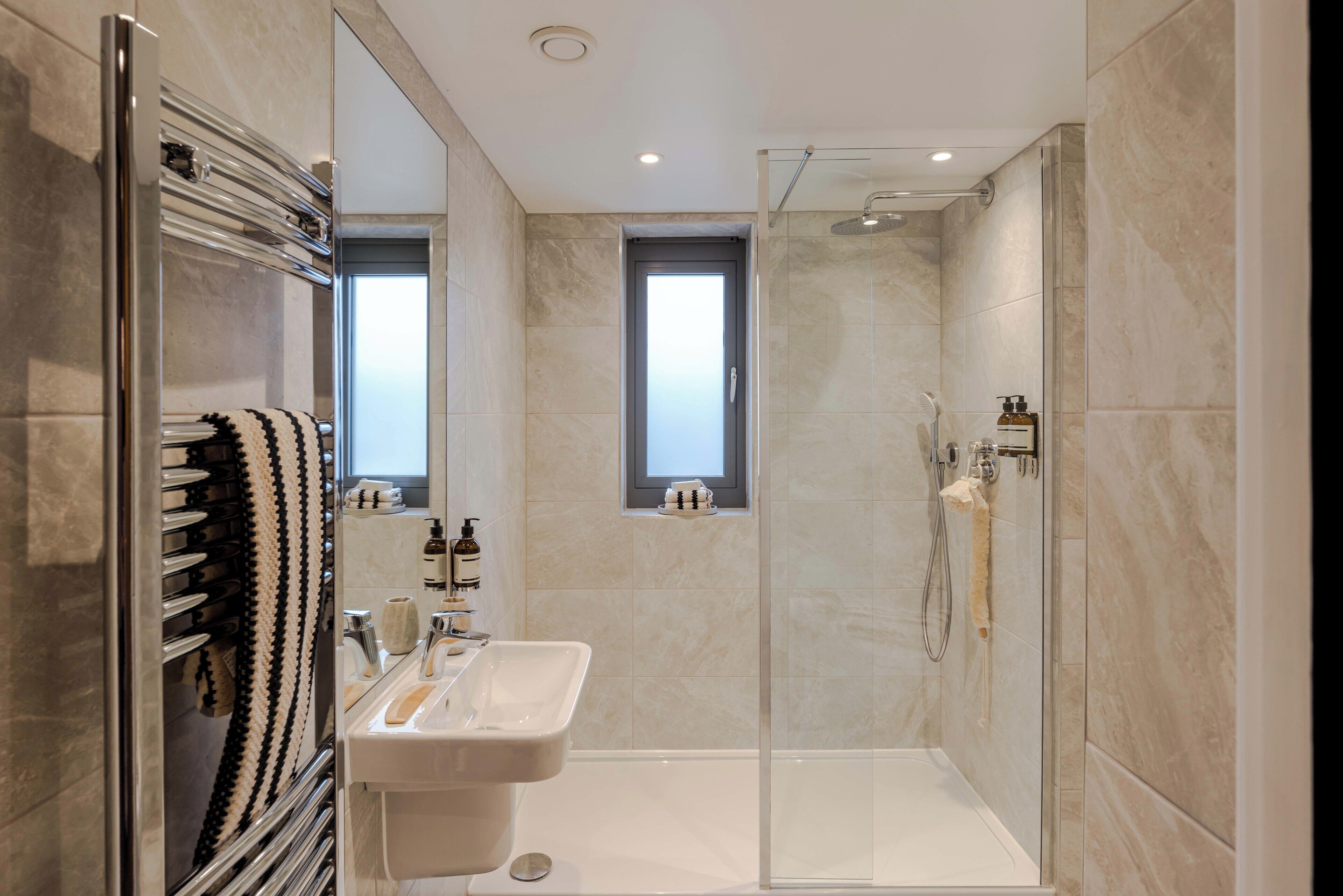A modern bathroom with a glass-enclosed shower, a sink with a mirror, and a towel rack.