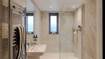 A modern bathroom with a glass-enclosed shower, a sink with a mirror, and a towel rack.