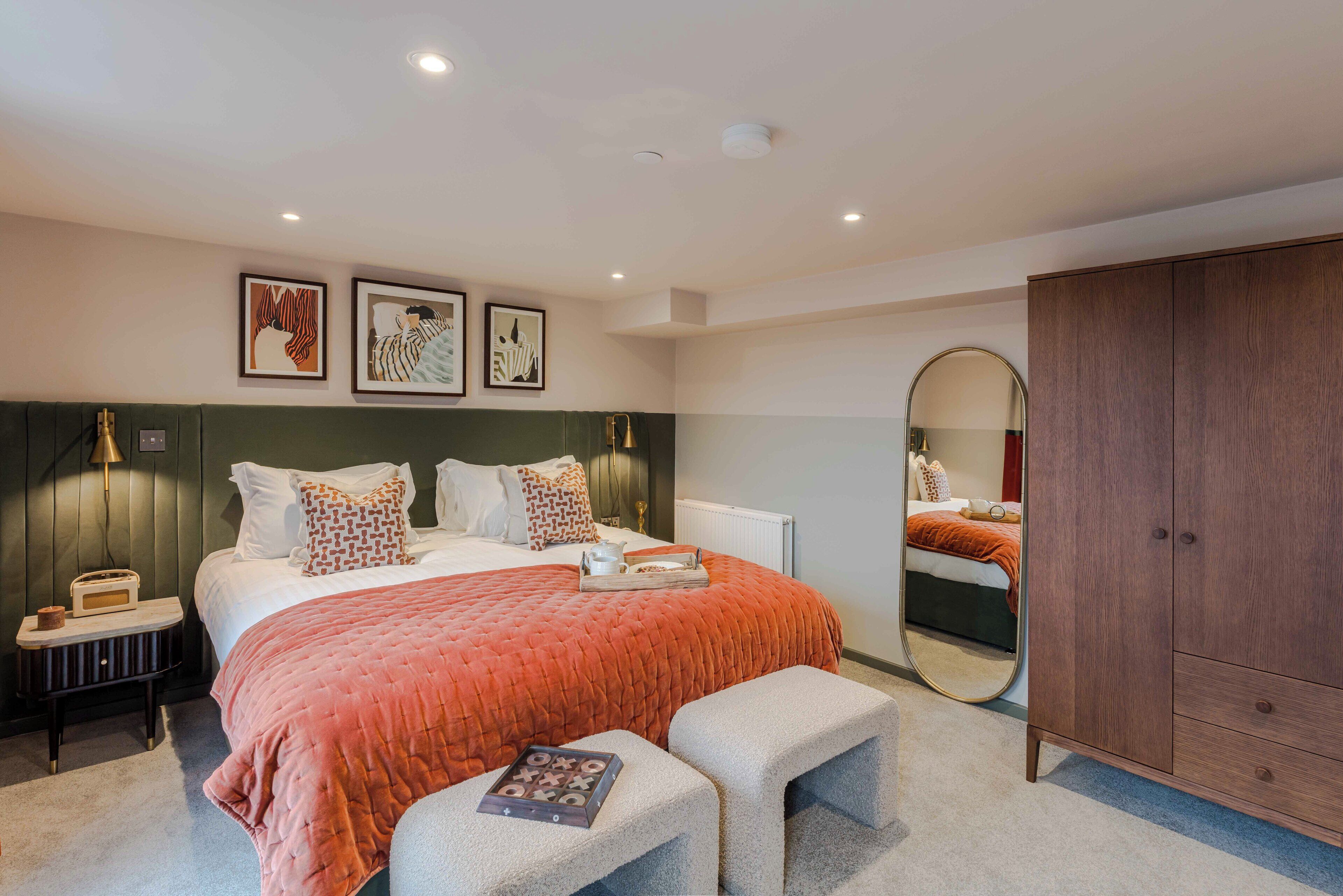 Un dormitorio moderno con una cama grande, mesitas de noche, un armario y obras de arte en las paredes.