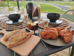 A breakfast table with croissants, jams, and a coffee pot.