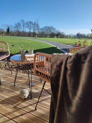 A patio with wicker furniture, a small table, and a decorative sheep sculpture.