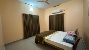 Ein Schlafzimmer mit Bett, Vorhängen, einer Klimaanlage und einem Deckenventilator.