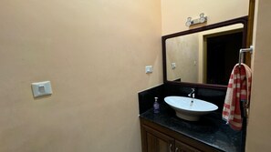 Ein Badezimmer mit einem weißen Waschbecken, einem Spiegel und einem Handtuchhalter.