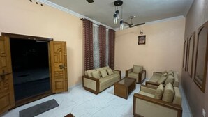 Ein Wohnzimmer mit einer Sofagarnitur, einem Couchtisch und einem Fernseher. Eine Tür führt zu einem Balkon.