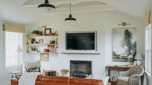 Una sala de estar con chimenea, televisor y un cuadro grande en la pared.