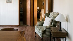 A room with a checkered armchair, a wooden side table with a lamp, and a wooden bench.