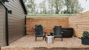 Un espace patio comprenant deux fauteuils Adirondack, une petite table ronde et une poubelle.
