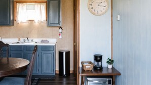 Una cocina compacta con armarios azules, una mesa de comedor de madera, una cafetera y un horno tostador.