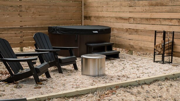 Un patio con sillas Adirondack, un jacuzzi y un cubo de metal.