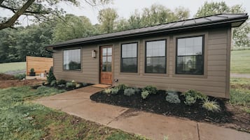 A single-story house with a front door, large windows, and a small porch area.