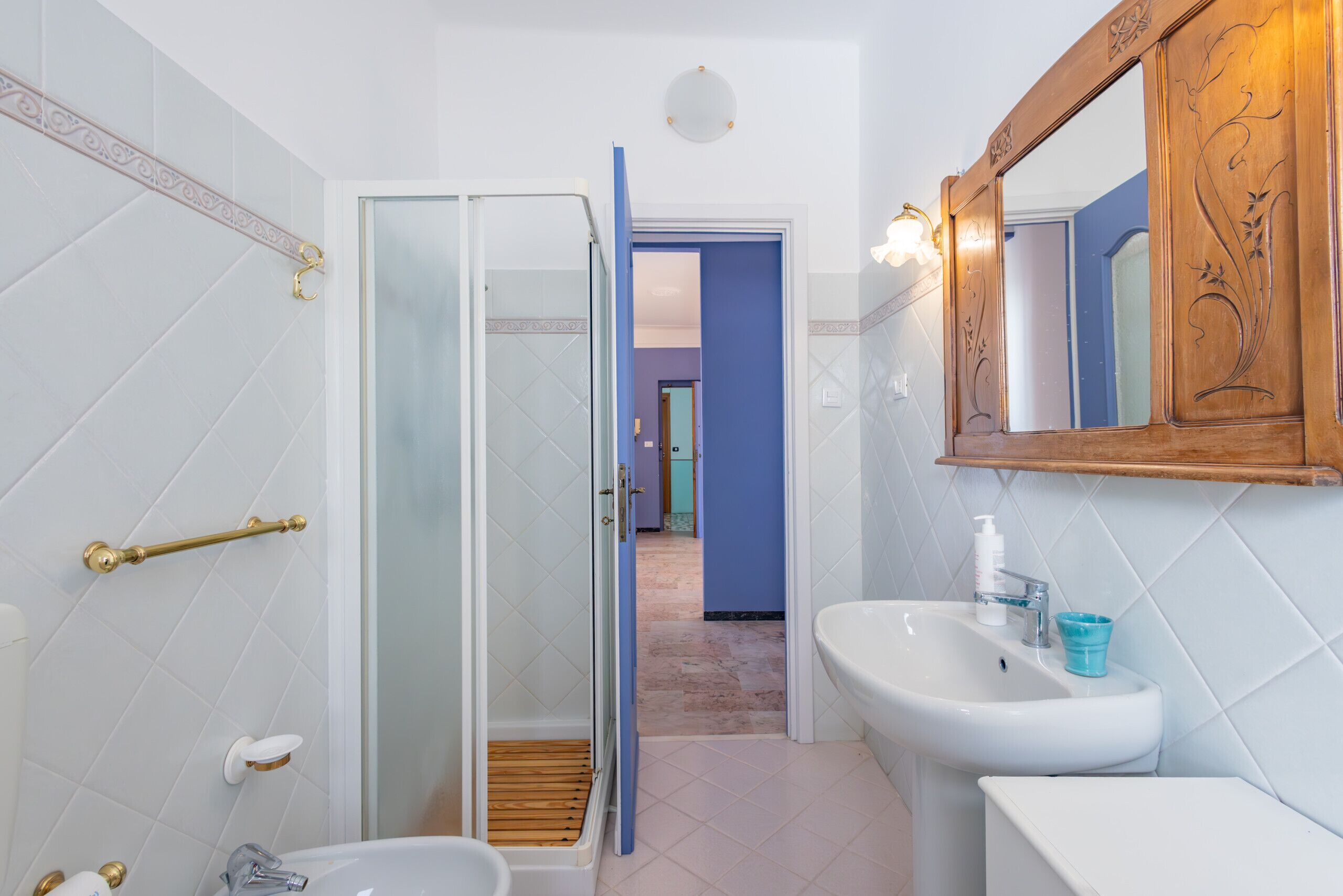 A bathroom with a glass shower enclosure, a sink with a mirror, and a toilet.