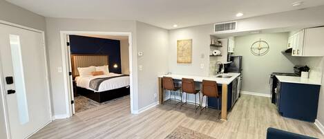 A compact living space with a bedroom, kitchenette, and a dining area.