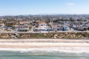 A coastal residential area with houses, a beach, and a rocky shoreline.