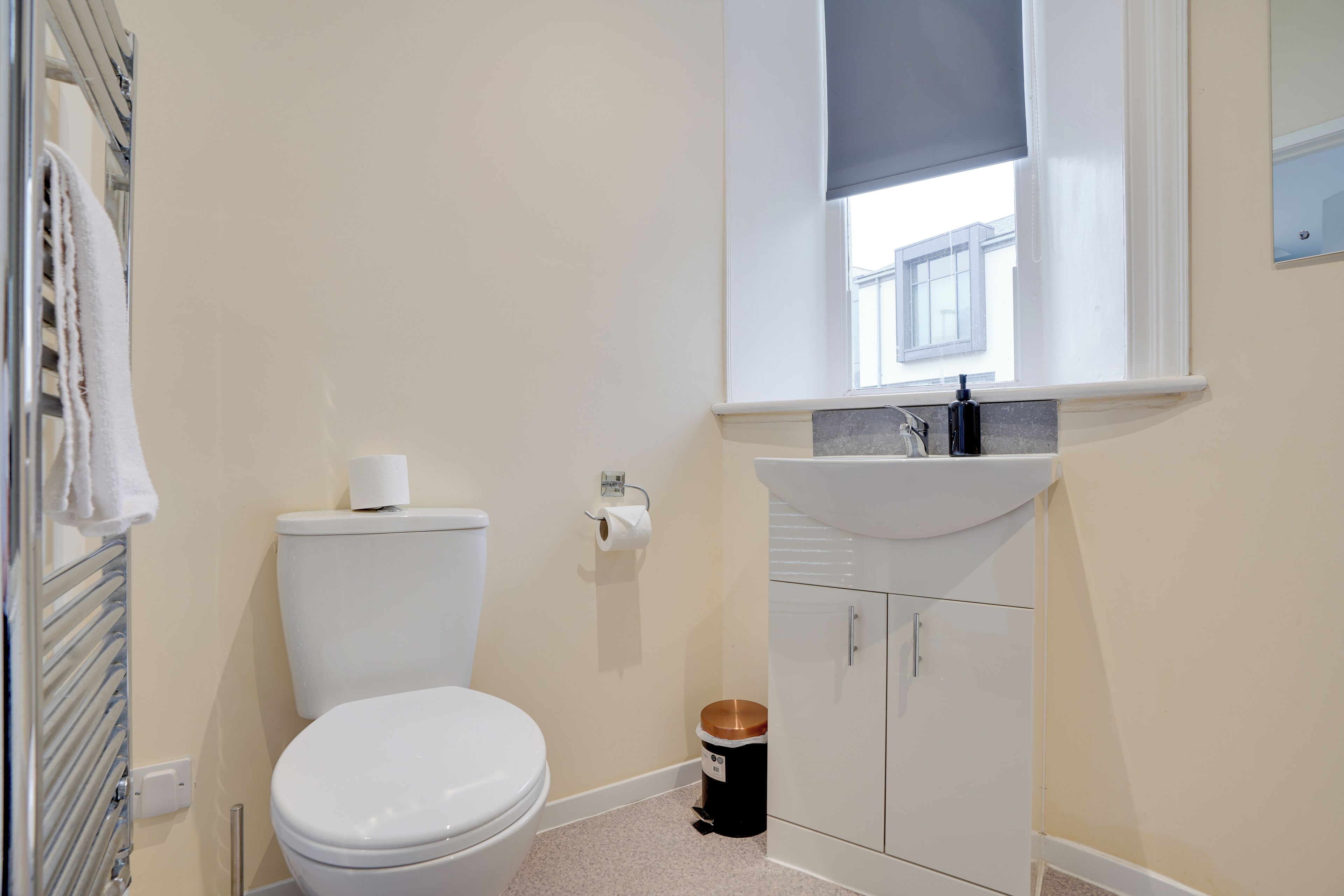 Een kleine badkamer met toilet, wastafel en raam.