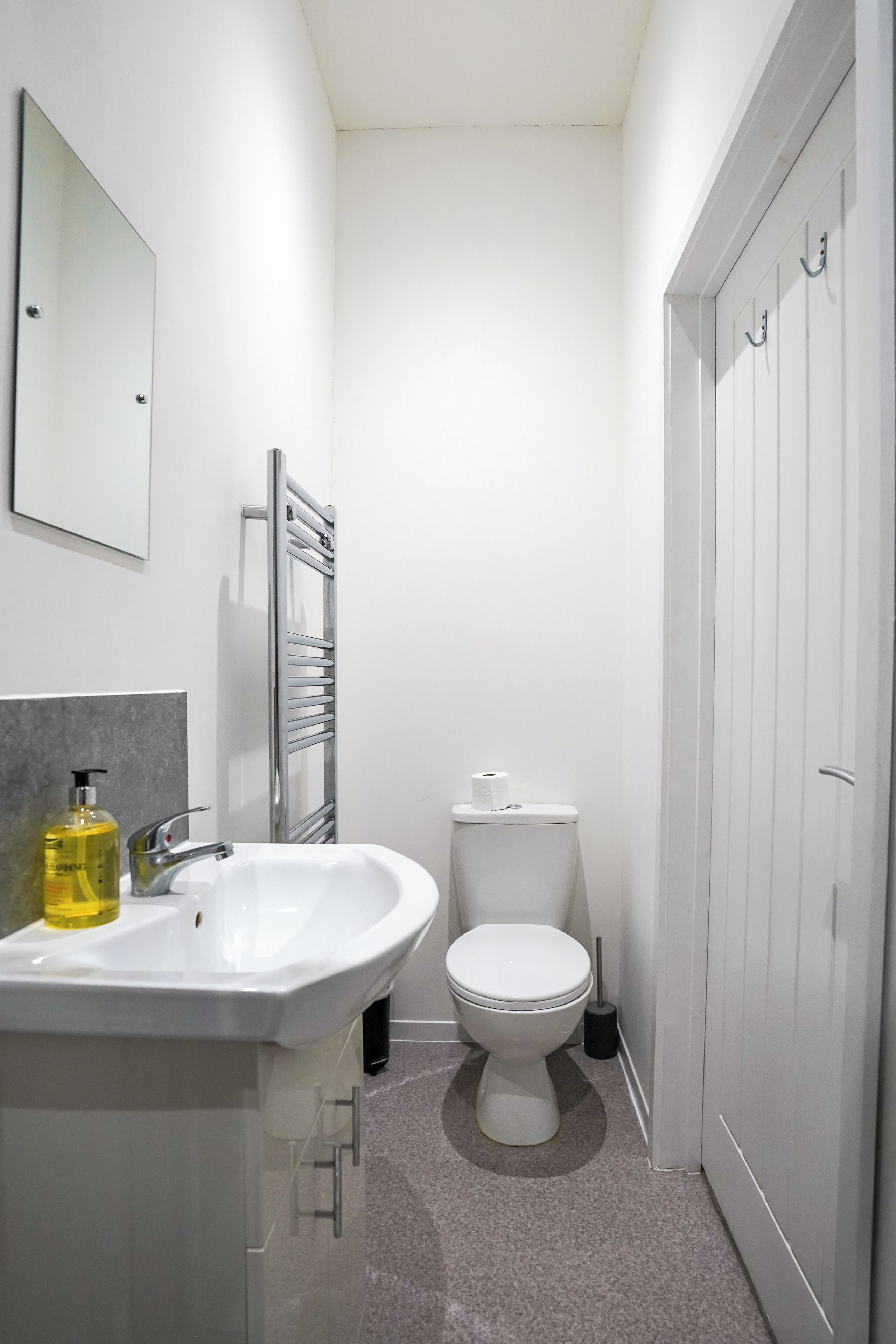 A modern bathroom with a white sink, mirror, and toilet.