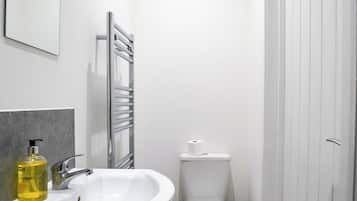 Un baño moderno con lavamanos, espejo y retrete blancos.