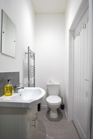A modern bathroom with a white sink, mirror, and toilet. - Homesly Guest Rooms - Self Checkin (Berwick-upon-Tweed)