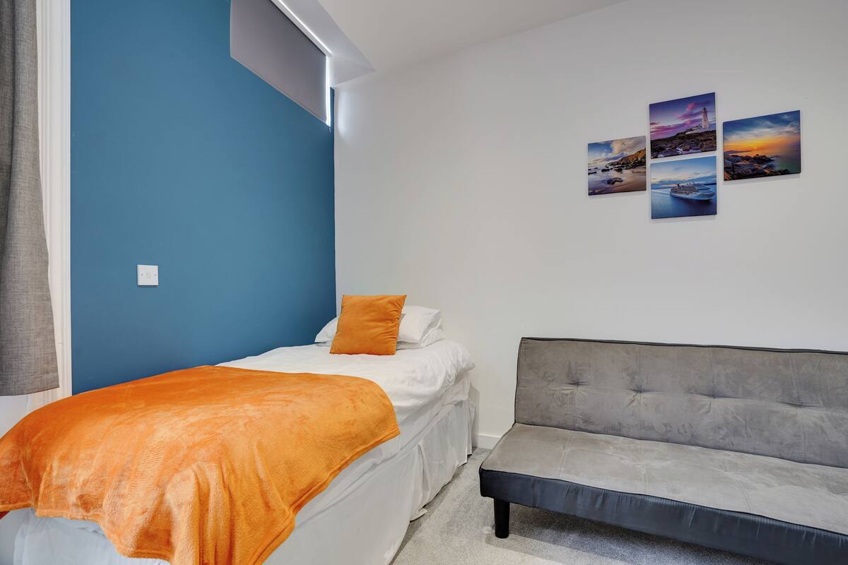 Un dormitorio con una cama, un sofá y una pared con cuatro cuadros.