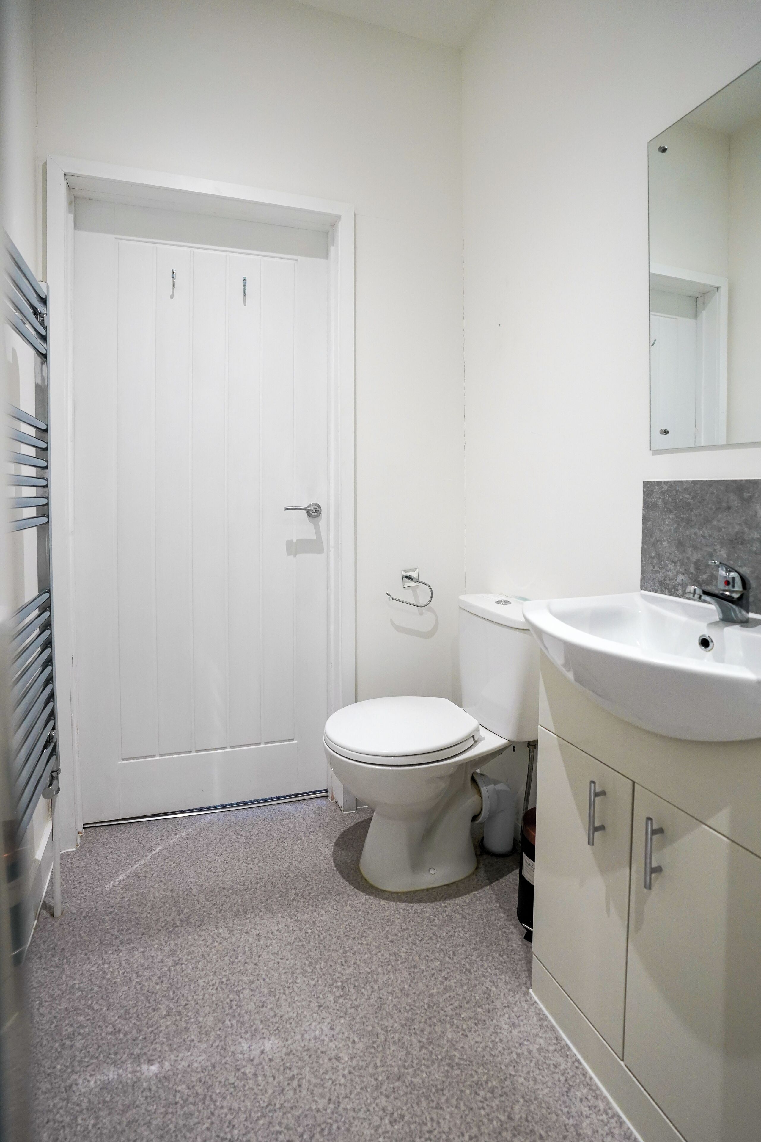 Un baño con inodoro blanco, lavamanos y espejo.