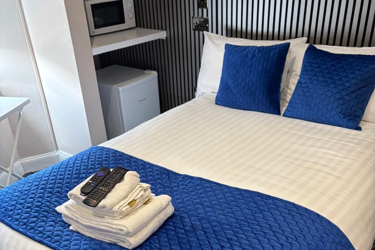 A hotel room with a bed, a microwave, and a small white cabinet.