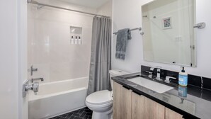 A modern bathroom with a bathtub, toilet, and sink. - Capitol Hill Suites - Unit 9 (Washington)