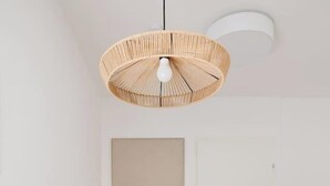 Ein moderner Essbereich mit einem weißen Tisch, Stühlen und einer hängenden Lampenschirm aus Weidengeflecht.