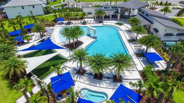 Een resort met een groot zwembad, ligbedden en palmbomen.