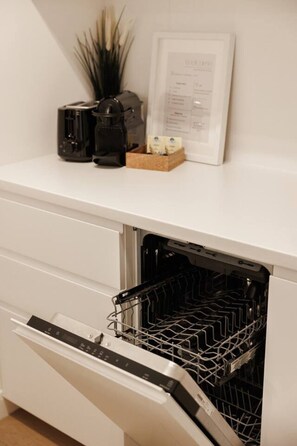 A kitchen with a built-in dishwasher, a coffee maker, and a framed menu on the countertop. - Cozy BOHO Loft, 10min to City Center, terrace (Wien)