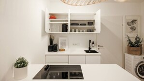 A modern kitchen with white cabinetry, a black stove, and a built-in sink.