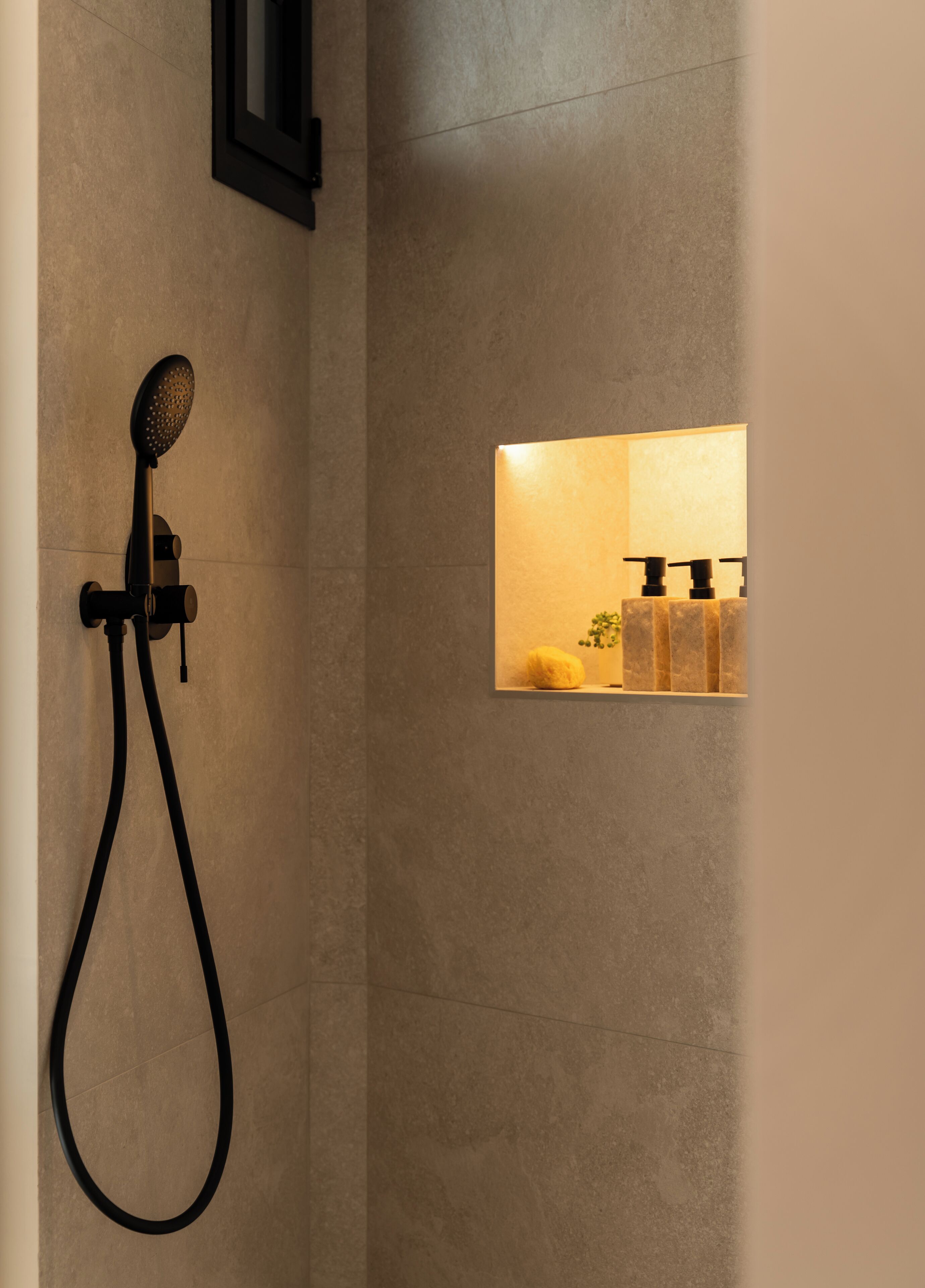 A shower with a handheld showerhead and a wall-mounted control.