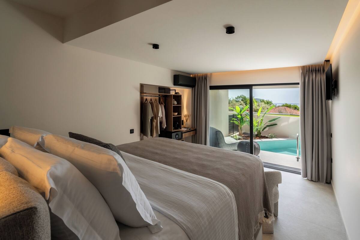 A bedroom with a large bed, a wardrobe, and a view of a swimming pool.