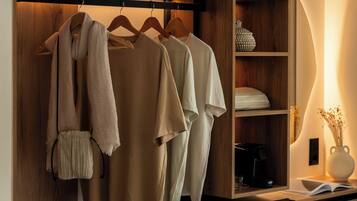 Un dormitorio con cama, un armario con ropa colgada, una mesita de noche con lámpara y un aire acondicionado instalado en la pared.