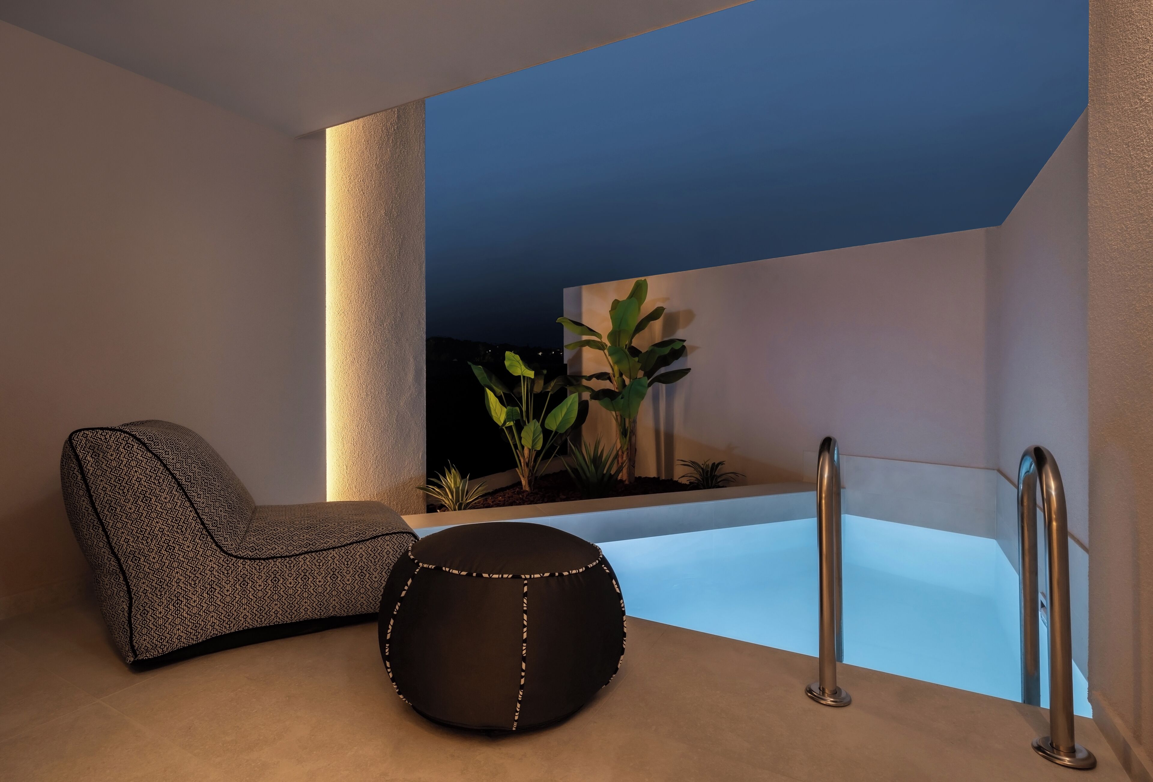 A modern bathroom with a bathtub, a chair, and potted plants.