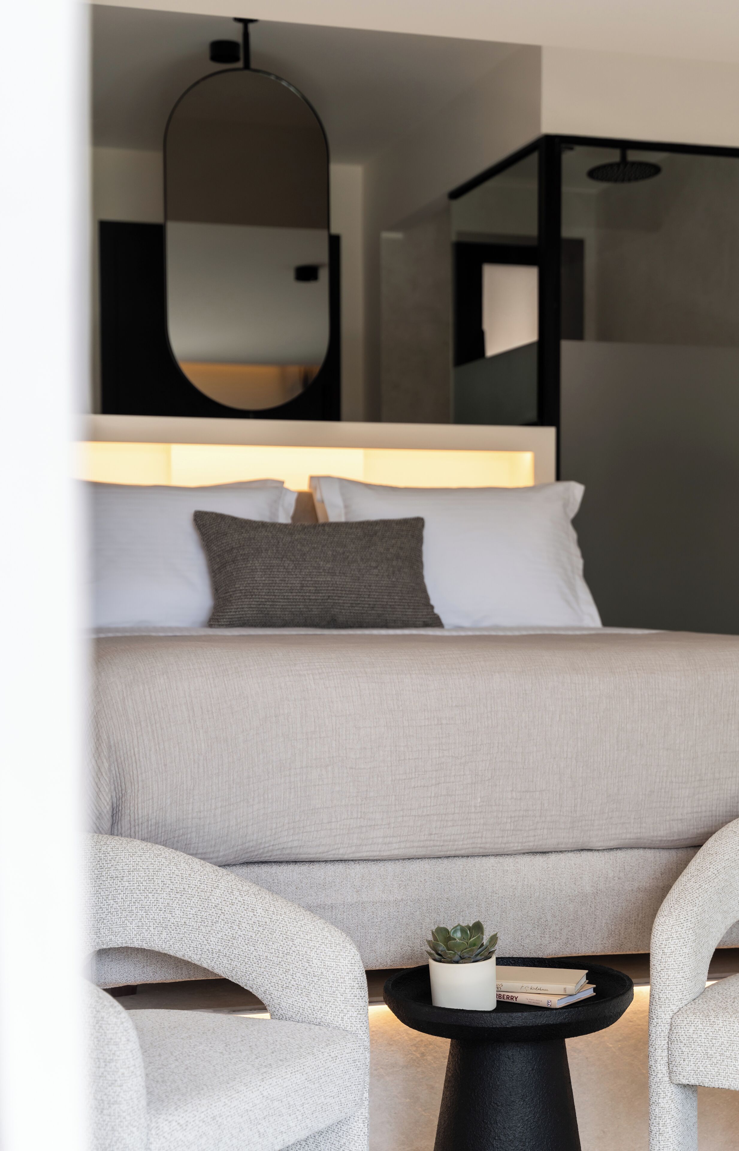 Un dormitorio moderno con cama, mesita de noche y espejo.