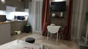 A compact kitchen with a dining area, a TV mounted on the wall, and a small table with chairs. - Lovely studio in Amélie-les-Bains. Ideal for a spa treatment in the heart of Vallespir! (Amélie-les-Bains-Palalda)