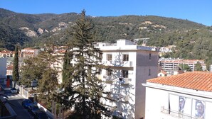 A building with multiple floors, balconies, and a view of a mountainous landscape. - Lovely studio in Amélie-les-Bains. Ideal for a spa treatment in the heart of Vallespir! (Amélie-les-Bains-Palalda)