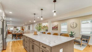 Una cocina moderna con una isla grande, armarios de madera e iluminación colgante.