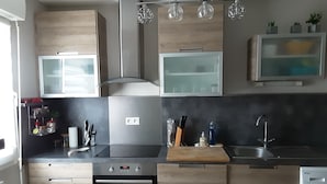 Eine moderne Küche mit Holzausstattung, einem Einbauofen, einer Spüle und einer Waschmaschine.