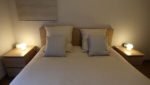 Ein ordentlich bezogenes Bett mit zwei Nachttischen, jeder Tisch mit einer Lampe.