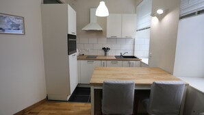 Eine kleine Küche mit weißen Schränken, einer Holz Arbeitsplatte und einer einzelnen Pendelleuchte.