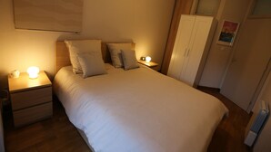 Ein Schlafzimmer mit einem großen Bett, Nachttischen mit Lampen, einem Beistelltisch, einem Kleiderschrank und einer Heizung.