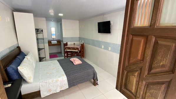 A bedroom with a bed, a desk, a chair, a TV, and a bathroom. - A Casa dos Mestres (Salvador)